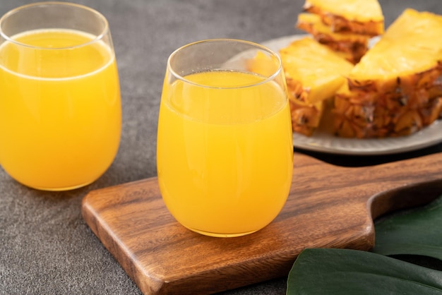 Zdjęcie Świeży pyszny sok ananasowy smoothie zimny napój w szklanym kubku na szarym tle stołu