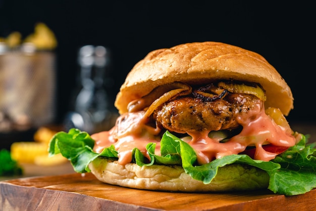 Świeży, smaczny burger z kurczaka na drewnianym stole, ciemny nastrój fotografii