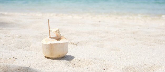 Świeży sok kokosowy i słoma na białym piasku na tle tropikalnej plaży Letnie koncepcje relaksu i wakacji