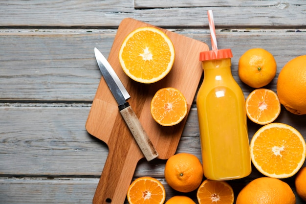 Świeży sok pomarańczowy w butelce z pomarańczami na rustykalnym drewnianym tle
