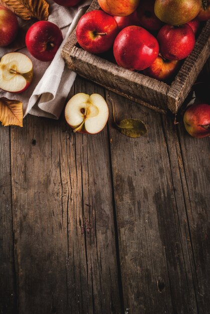 Zdjęcie Świeży surowy cały i pokrojony organicznie rolni czerwoni jabłka w starym drewnianym łęku n starym drewnianym wieśniaka stole