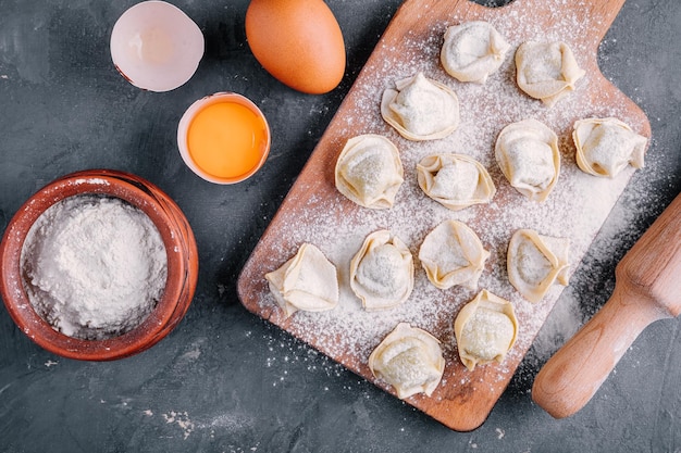 Świeży, Surowy Domowy Makaron Tortellini Lub Ravioli Na Ciemnym Tle