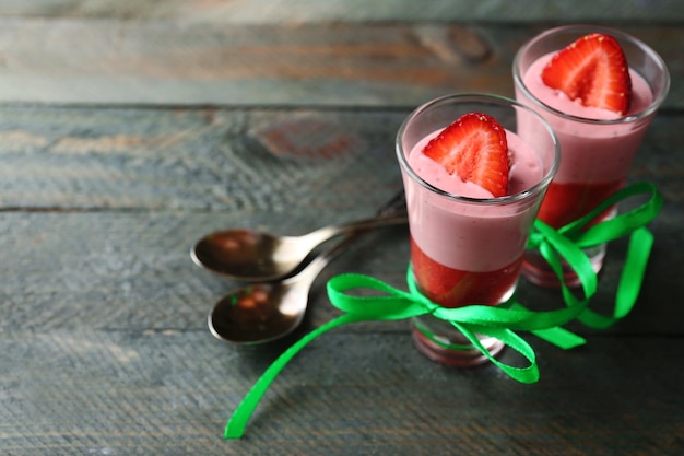 Zdjęcie Świeży truskawkowy jogurtowy deser w szkle na koloru drewnianym tle selekcyjna ostrość