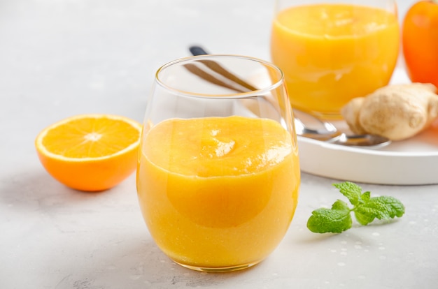 Świeży zdrowy smoothie z persimmon, pomarańcze i imbirem na szarość, betonujemy tło.