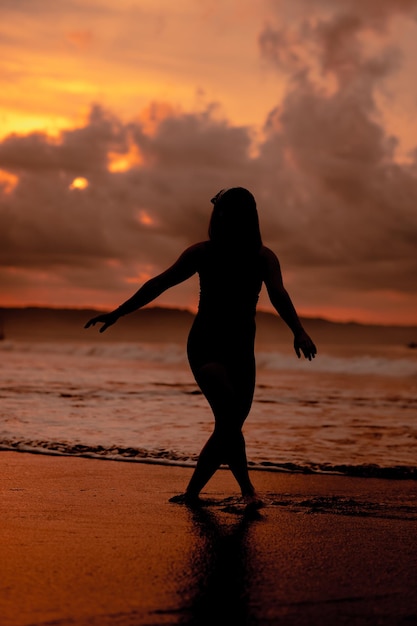 Sylwetka azjatyckiej kobiety bawiącej się w wodzie na plaży z silnymi falami