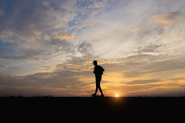 Sylwetka człowieka szczęśliwego spaceru o zachodzie słońca.