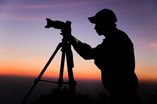 Sylwetka fotografa ze statywem Młody Indianin robi zdjęcie aparatem