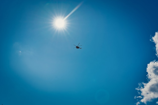 Sylwetka helikoptera na tle błękitnego nieba z chmurami