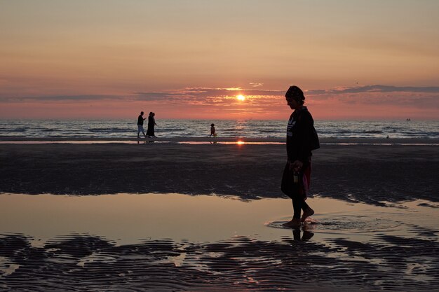 Sylwetka kobiety stojącej na plaży podczas zachodu słońca