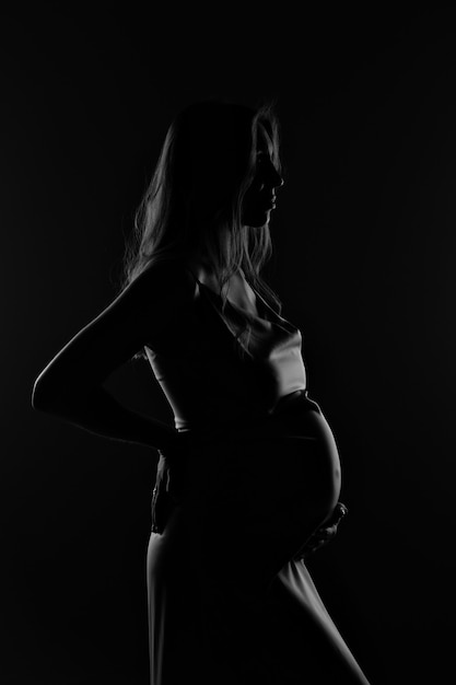 Sylwetka kobiety w ciąży na czarnym tle