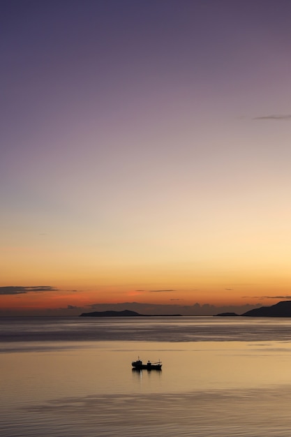 Sylwetka łodzi rybackiej płynącej po morzu podczas zachodu słońca z pięknym niebem