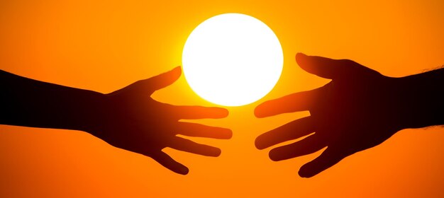 Sylwetka męskich i kobiecych dłoni na tle zachodzącego słońca koncepcja komunikacji i dążenia do bliskości w społeczeństwie i rodzinie