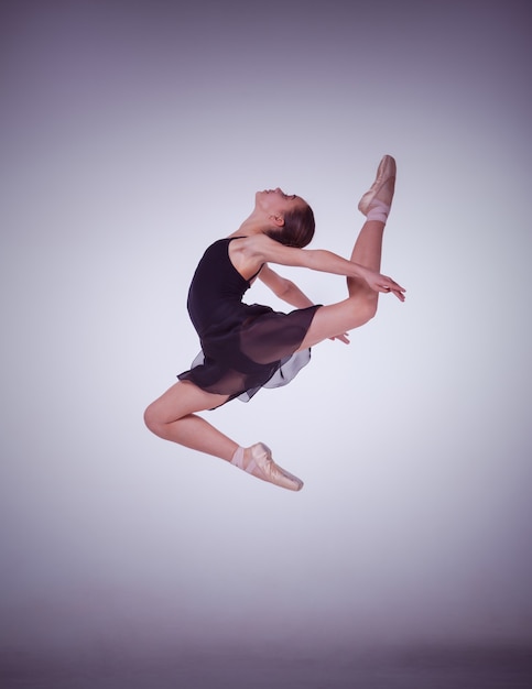 Sylwetka młoda tancerka baletowa skoki na liliowym tle.