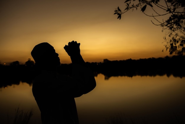 Sylwetka Młody azjatycki muzułmański mężczyzna modlący się o zachodzie słońcaKoncepcja festiwalu Ramadan