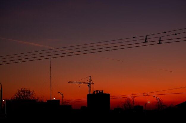 Sylwetka nocnego miasta z dźwigiem budowlanym na tle zachodu słońca