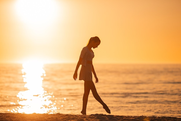 Sylwetka pięknej dziewczyny, ciesząc się pięknym zachodem słońca na plaży
