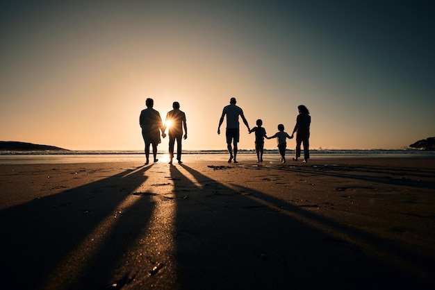 Sylwetka plaży i duża rodzina trzymająca się za ręce o zachodzie słońca na wakacjach lub wakacjach na morzu lub oceanie razem Podróżuj miłością lub cieniem ludzi o wschodzie słońca, wspierając wolność i wiązanie przez makietę wody
