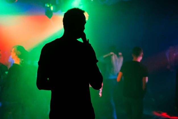 Sylwetka prezentera z mikrofonem na scenie klubu nocnego na koncercie