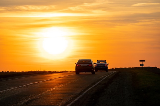 Sylwetka samochodu na drodze na tle słońca Samochód jedzie autostradą podczas zachodu słońca Koncepcja podróży i wolności