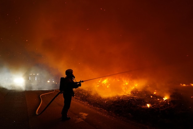 Sylwetka strażaka przeciwko pożarowi w nocy