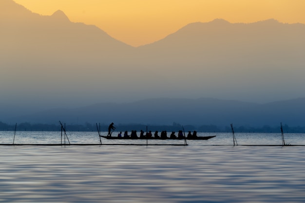 Zdjęcie sylwetka turyści na drewnianej łodzi przy phayao jeziorem, tajlandia.