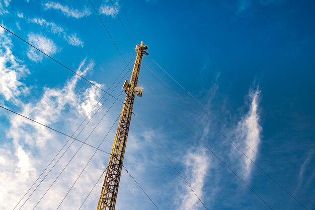 Sylwetka wieży telekomunikacyjnej na tle niesamowicie pięknego błękitnego nieba z rozmytymi, jasnymi, białymi chmurami