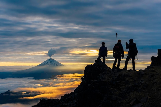 Sylwetki alpinistów o wschodzie słońca w tle wulkanu Cotopaxi