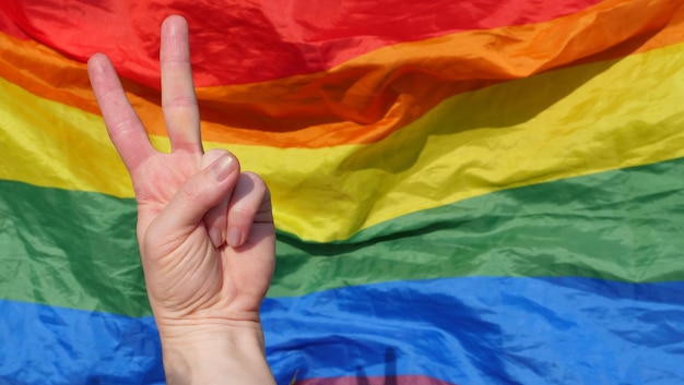 Symbol gestu ręki pokoju na tle tęczowej flagi lgbt w miesiącu dumy godności i różnorodności
