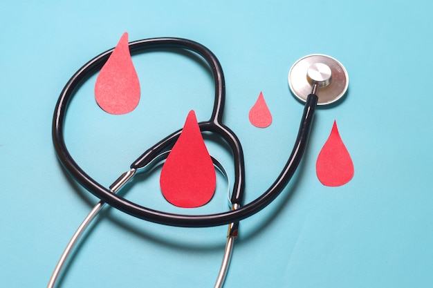 Symbol kropli krwi ze stetoskopem na niebieskim tle Dzień hemofilii koncepcja dnia dawcy krwi