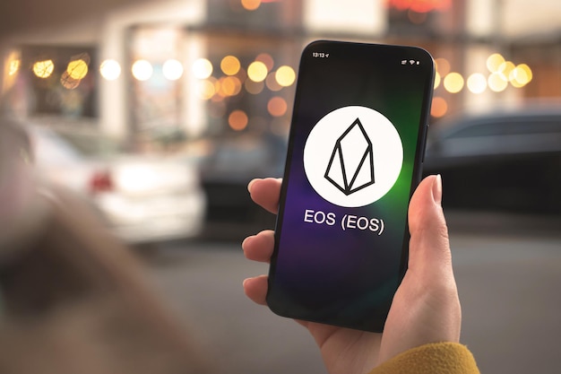 Symbol Kryptowaluty Eos, Logo. Koncepcja Biznesowa I Finansowa. Ręka Ze Smartfonem, Ekran Z Zbliżeniem Ikony Krypto