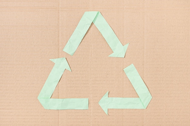 Zdjęcie symbol recyklingu wykonany z papieru wyciętego na tekturowej teksturze tła