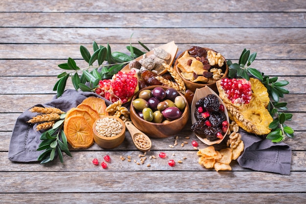 Zdjęcie symbole judaistycznego święta tu biszwat, rosz haszana nowy rok drzew. mieszanka suszonych owoców, daktyl, figa, winogrono, jęczmień, pszenica, oliwka, granat na drewnianym stole. skopiuj tło przestrzeni
