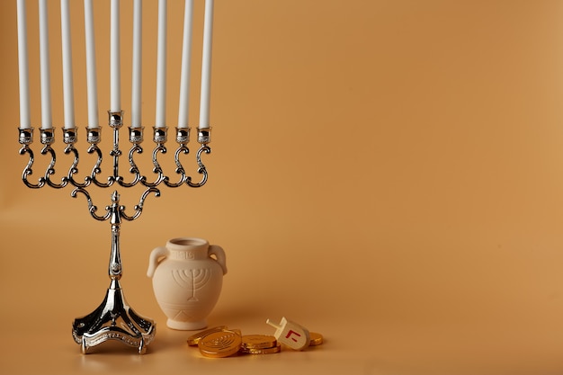 Symbole żydowskiego święta na brzoskwiniowym tle chanuka słoik świece cukierki drewniany dreidel
