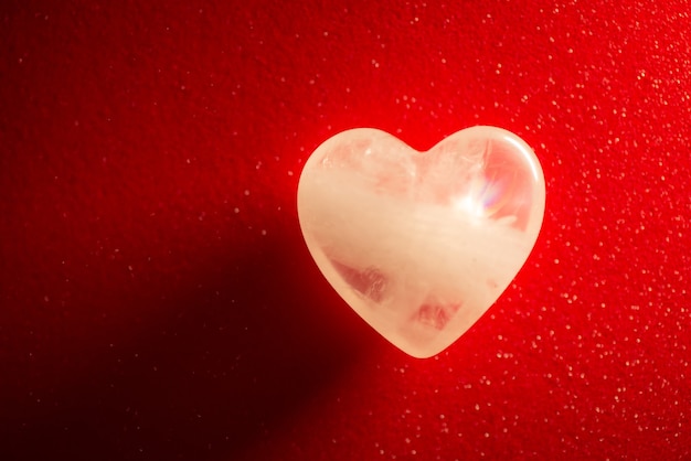 Symboliczne zdjęcie przezroczystego kamienia w kształcie serca na czerwonym tle