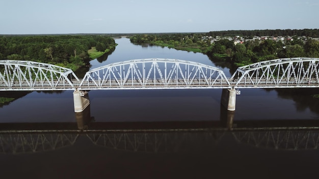 Symetryczny widok z lotu ptaka stalowego mostu kratownicowego dla pociągów przez rzekę