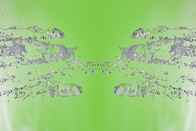 Symetryczny wzór zatrzymanych kropelek wody z przezroczystymi strumieniami na zielonym tle