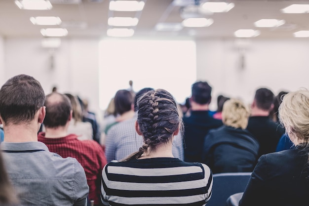 Sympozjum biznesu i przedsiębiorczości Kobieta przemawiająca na spotkaniu biznesowym Publiczność w sali konferencyjnej Widok z tyłu nierozpoznanego uczestnika na widowni Kopiowanie miejsca na białym ekranie