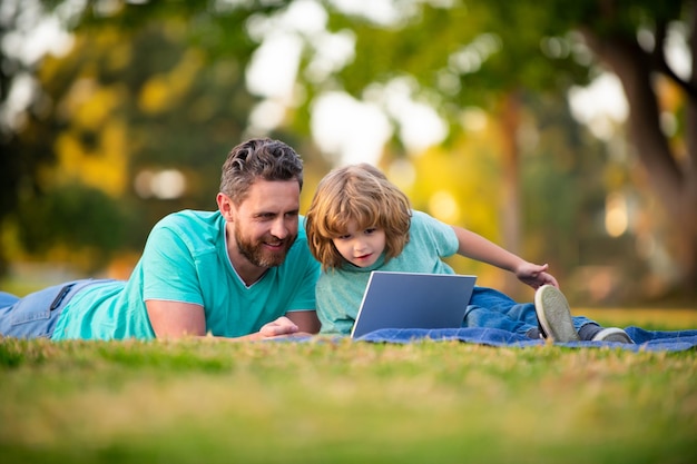 Syn z ojcem ogląda lekcję na laptopie na świeżym powietrzu
