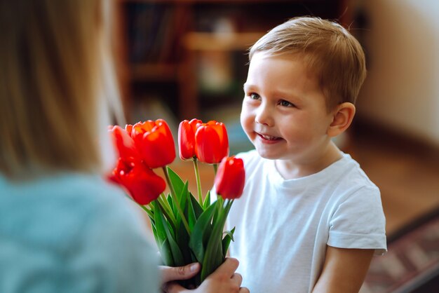 Synek gratuluje mamie i daje bukiet kwiatów tulipanów. Szczęśliwego dnia Matki.