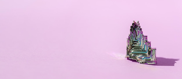 Syntetyczny bizmut Bizmutowy kryształ z opalizującym filmem tlenkowym na różowym tle z bliska na białym tle Niesamowita kolorowa błyszcząca tęcza Mineralny kamień bizmutu Banner