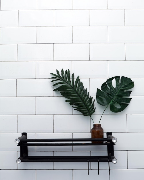 Szafka łazienkowa na ścianie z płytek ze sztucznymi roślinami. Minimalistyczna koncepcja wnętrza.