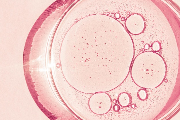 Szalka Petriego Kubek Petriego z płynem Pierwiastki chemiczne olej kosmetyki Żel cząsteczki wody wirusy Zbliżenie Na różowym tle