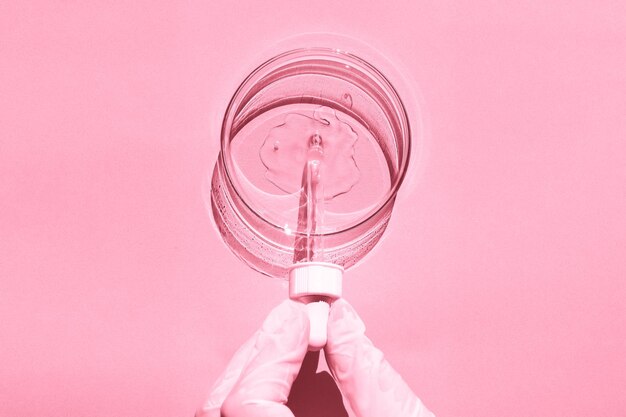 Szalka Petriego Z przezroczystym żelem Ręka w rękawiczce trzyma dozownik pipety Na różowym tle