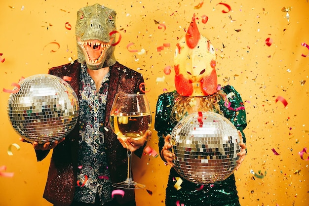 Zdjęcie szalona para dobrze się bawi trzymając kule dyskotekowe i kieliszek do szampana na imprezie główny nacisk położony jest na rękę trzymającą kieliszek