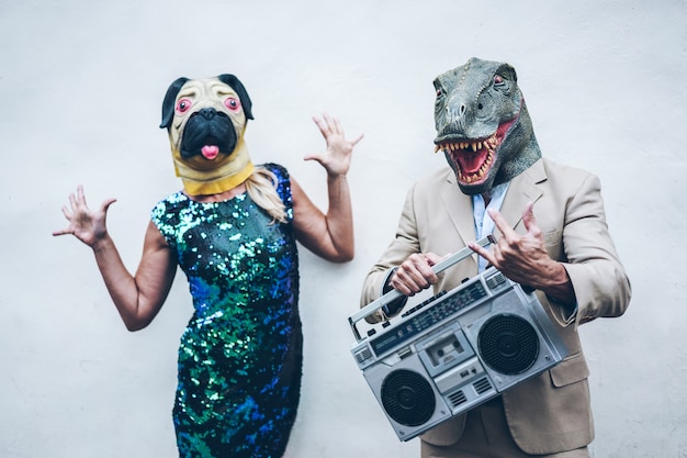 Szalona para starszych tańcząca na imprezę ubrana w T-Rex i maskę z kurczaka - Starzy modni ludzie bawią się słuchając muzyki z boombox stereo