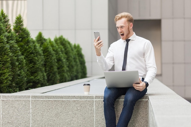 Szalony imbirowy biznesmen krzyczy w smartfonie