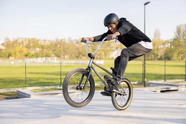 Szalony rowerzysta jeździ na swoim niskim rowerze w skateparku bmx podnosząc przednie koło i będąc w powietrzu