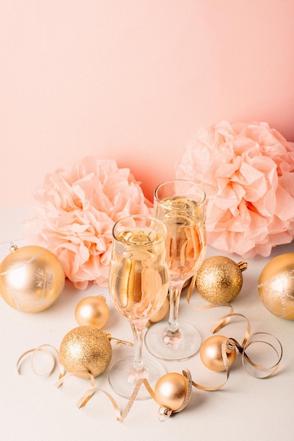 Szampan w szklanych kielichach złote balony gwiazdki serpentyna pastelowe delikatne różowe tło Noworoczna świąteczna koncepcja
