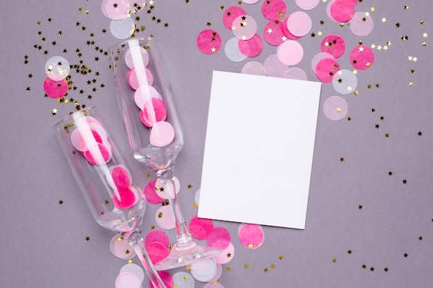 Zdjęcie szampańscy szkła i karta z różowymi confetti