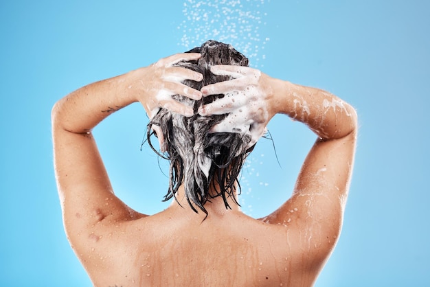 Szampon wodny i kobieta myjąca włosy na niebieskim tle Pielęgnacja włosów i higiena rano Modelka pod prysznicem czyszcząca mydło i piankę do włosów bieżącą wodą dla czystego, świeżego piękna w studio